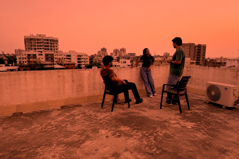 Three friends talking on a residential rooftop terrace.