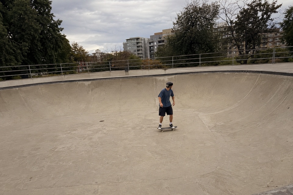 A skateboarder riding across a concrete bowl under an overcast sky. Processed with Meridian SLR 35 · Golden Hour 200.