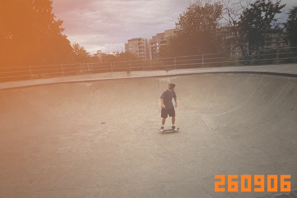 A skateboarder riding across a concrete bowl under an overcast sky.